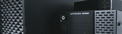 a close-up on the grilles at front of two servers standing vertically side-by-side, at a slight angle. the left server is all black with a coarse grille, the right server is a dell optiplex 9020 with a black IO panel and medium-density silver grille, and an external storage device sitting on top of it which also has a mid-density black grille on the front